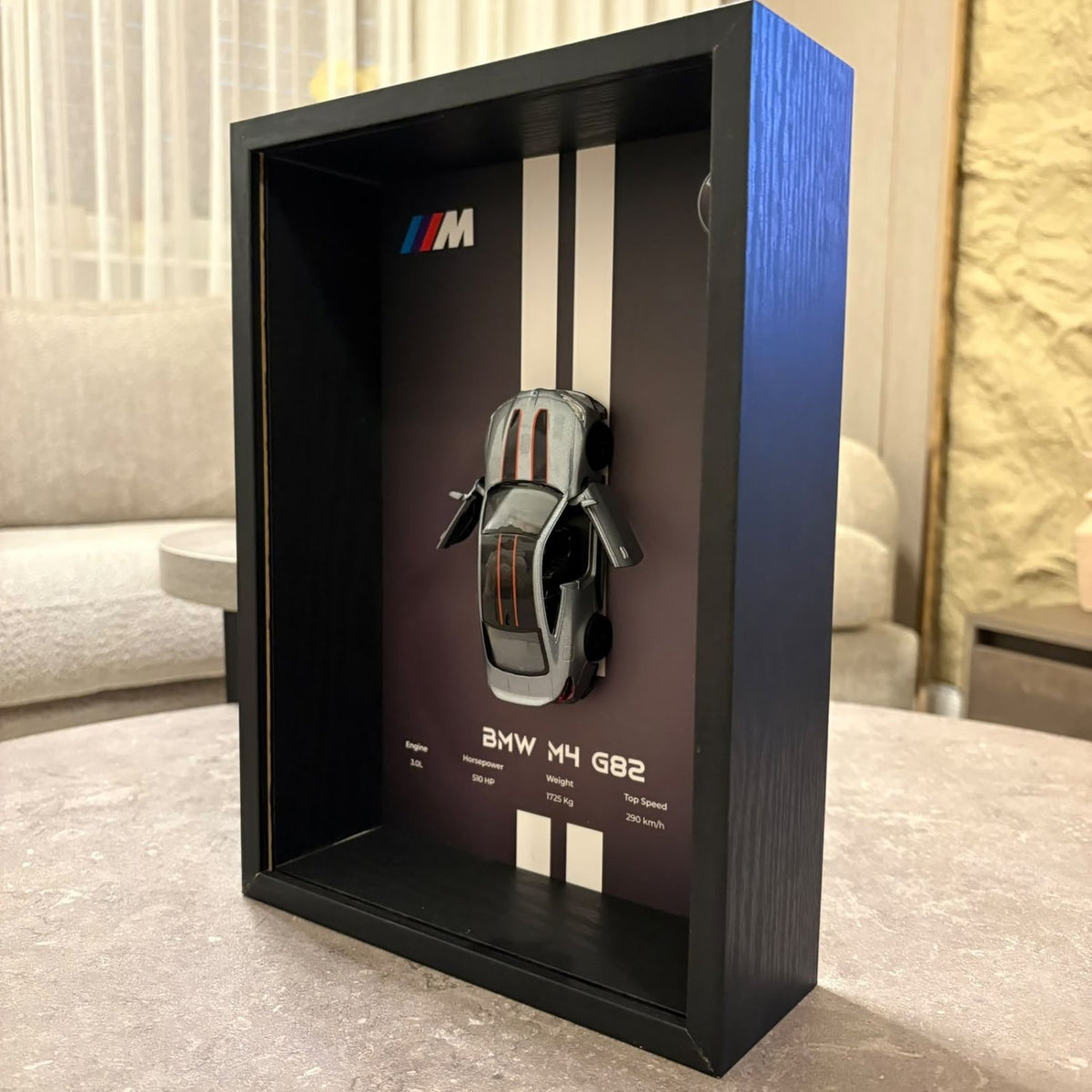 BMW M4 3D Framed Diecast Wall Art in a 32cm x 23cm black shadow box frame, featuring a grey 1:32 scale model car with open doors against an M-Power design background with performance stats.