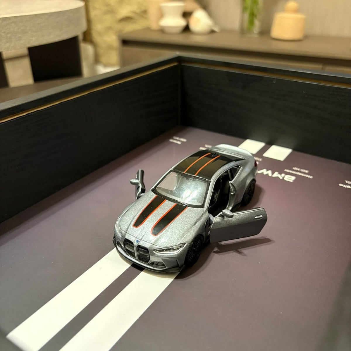 BMW M4 3D Framed Diecast Wall Art in a 32cm x 23cm black shadow box frame, featuring a grey 1:32 scale model car with open doors against an M-Power design background with performance stats.