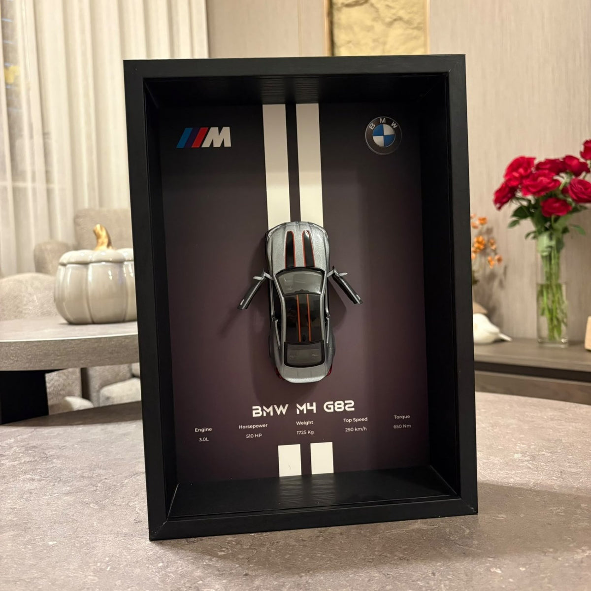 BMW M4 3D Framed Diecast Wall Art in a 32cm x 23cm black shadow box frame, featuring a grey 1:32 scale model car with open doors against an M-Power design background with performance stats.