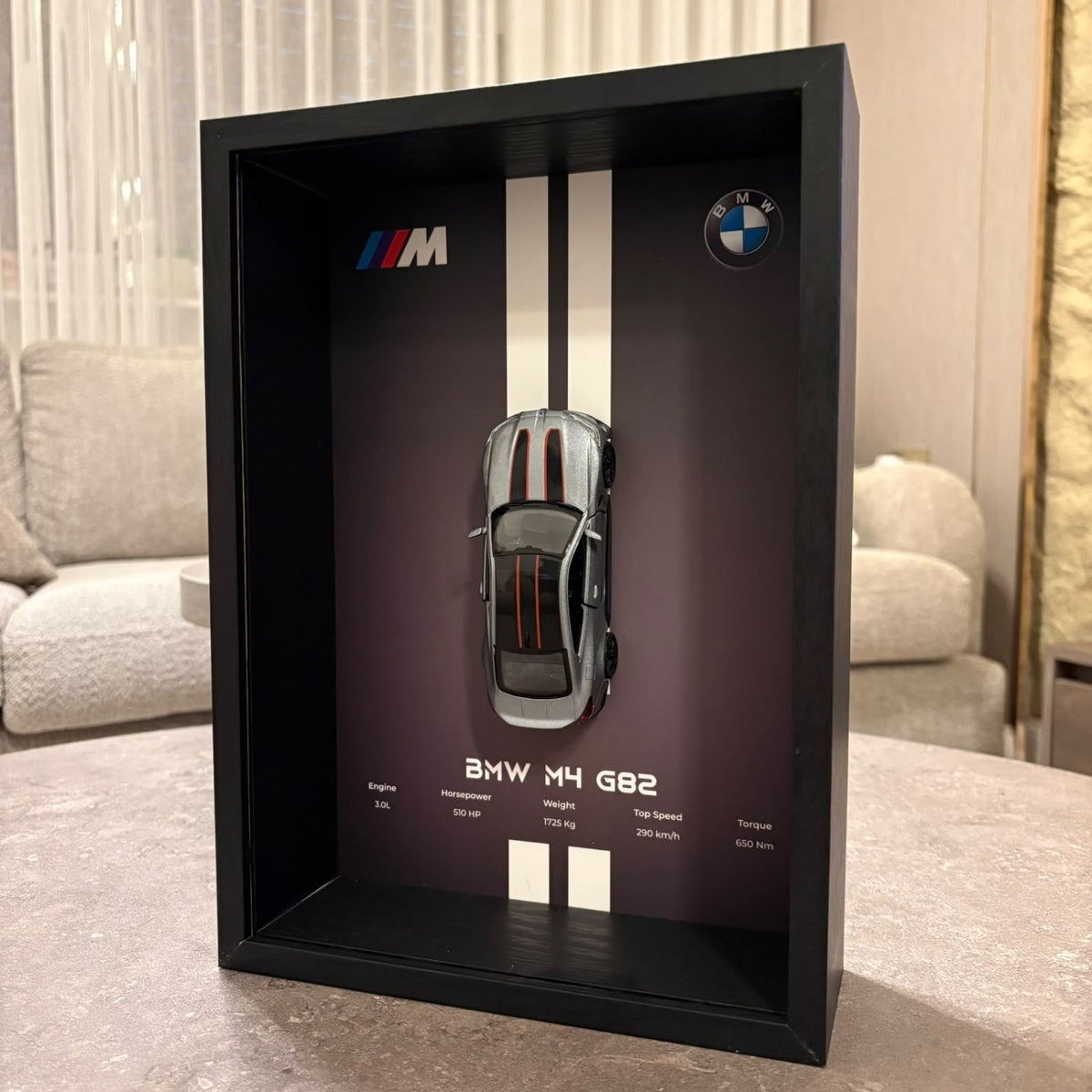 BMW M4 3D Framed Diecast Wall Art in a 32cm x 23cm black shadow box frame, featuring a grey 1:32 scale model car with open doors against an M-Power design background with performance stats.