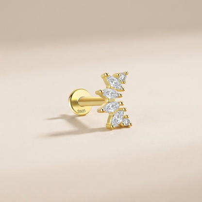 A single gold post piercing stud earring with marquise-cut clear gemstones, shown on a warm beige background.